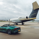 A photo of a Bentley convertible parked next to a matching aircraft.